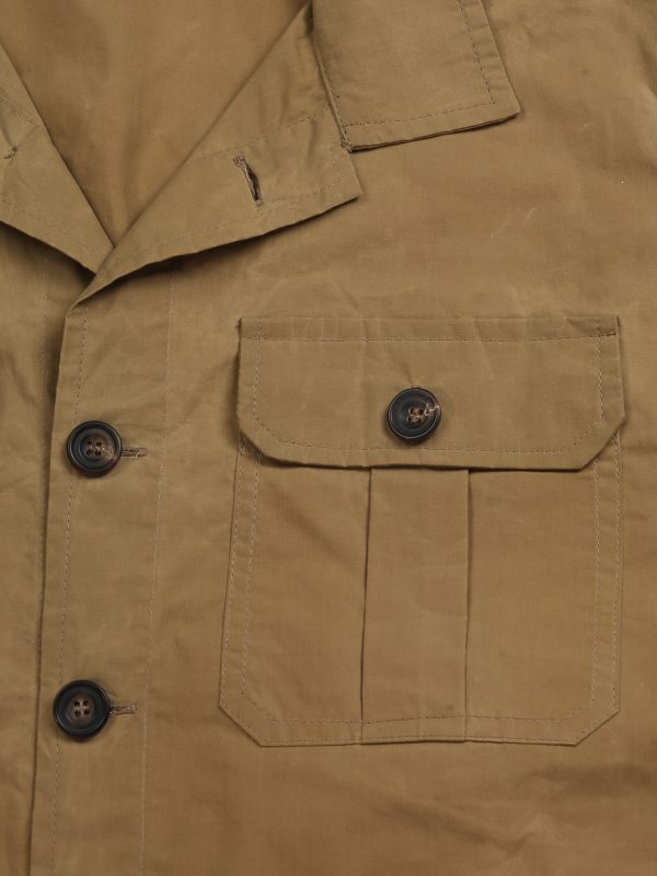 Close-up of the beige waxed cotton TARGA Jacket showing the pleated flap chest pocket and horn-style buttons.