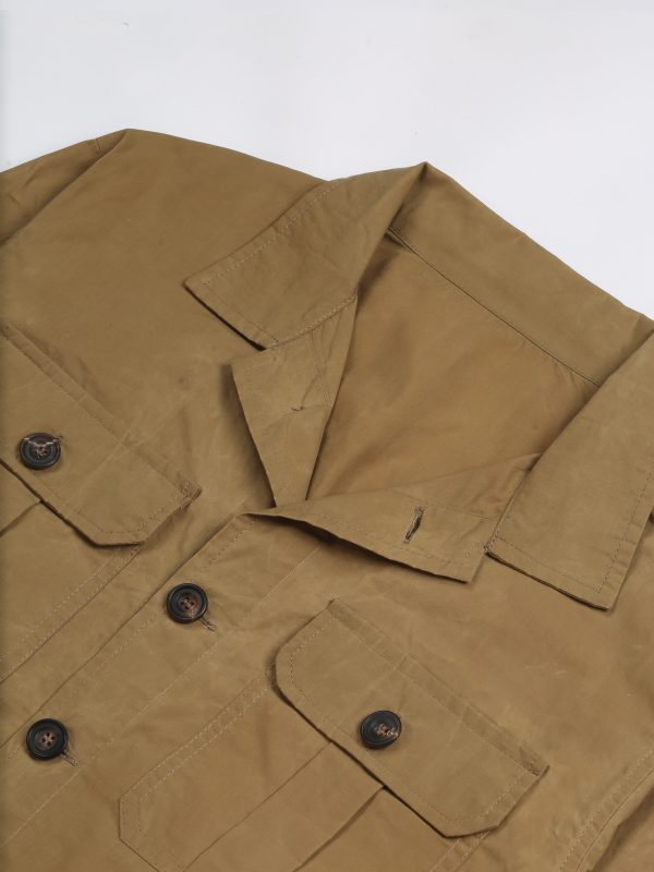 Detail of the beige waxed cotton TARGA Jacket showing the open collar, button closure and pleated chest pockets.